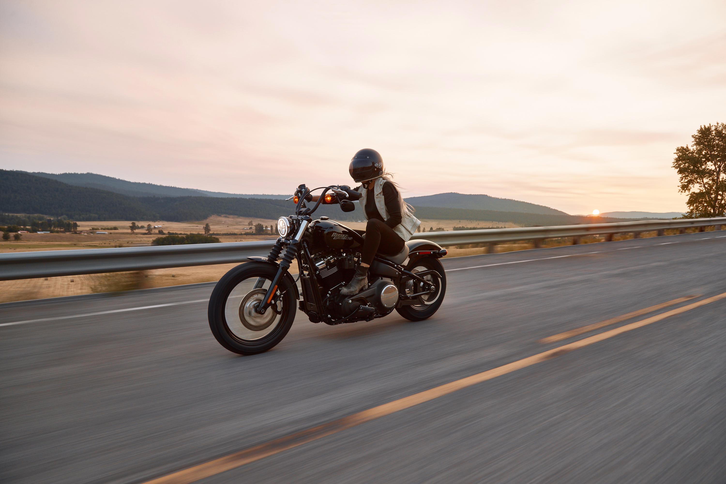 Motorcyclist riding away from a sunset in the fall.